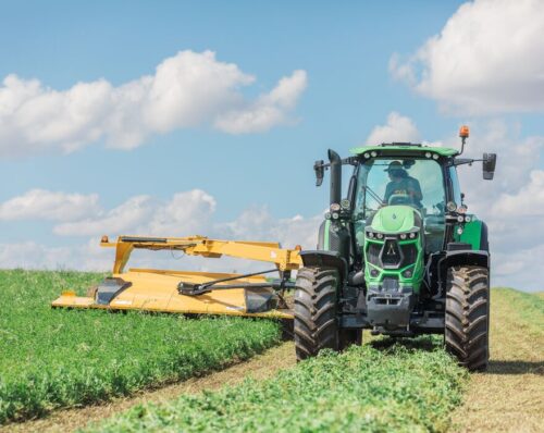 A tractor pulls a Vermeer mower conditioner in a field.