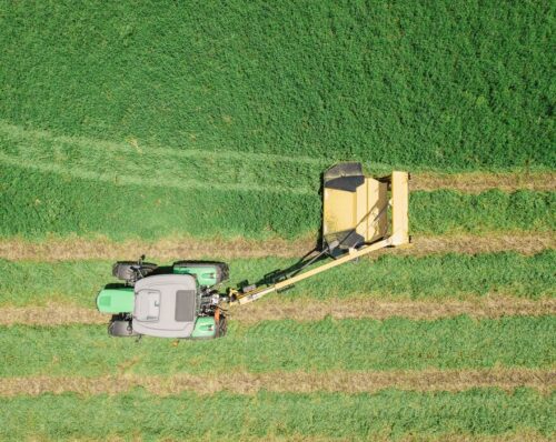 A Vermeer mower conditioner being pulled by a tractor in a field.